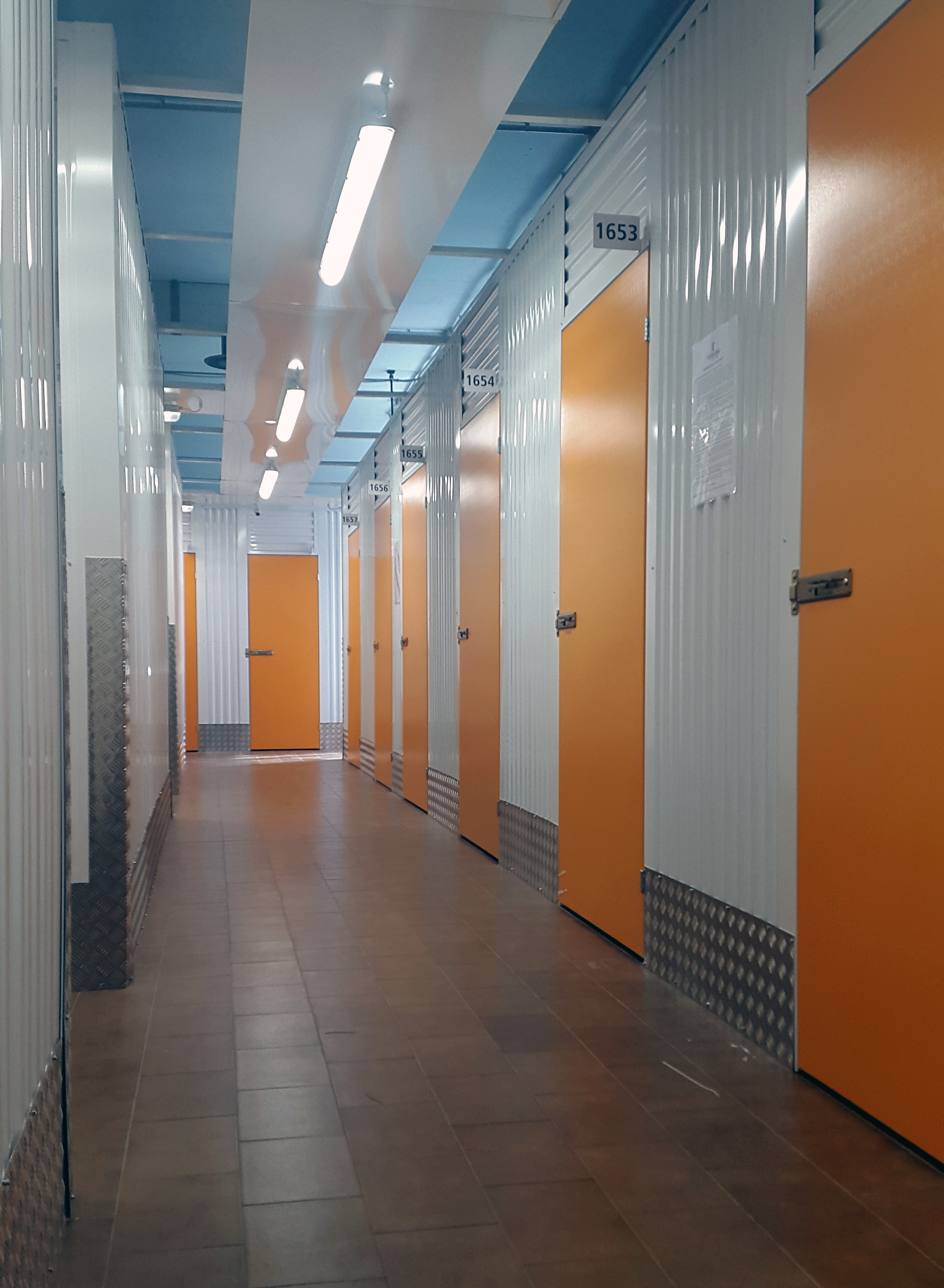 File di box self storage nuovi con porte arancioni in corridoio pulito
